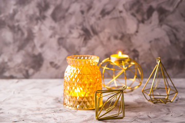 Golden Christmas decorations and candlesticks with burning candles on gray background. Festive minimalism. Copy space