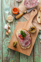 Homemade headcheese on a bread with pickles and sauces
