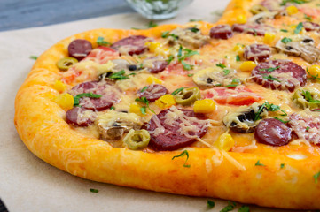 Tasty pizza in a heart shape with mushrooms, salami, pepperoni, olives, corn. Close up