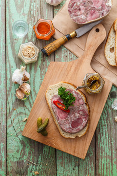 Homemade headcheese on a bread with pickles and sauces