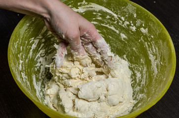 The cook kneads the dough with flour