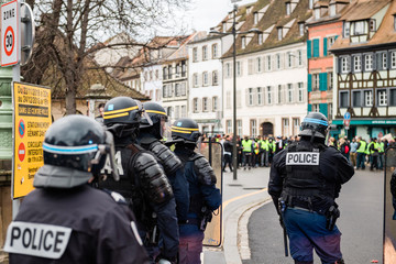 Rear view of police officers securing the zone in frong of the Yellow vests movement protesters on...