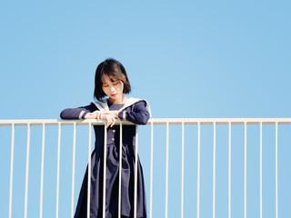 Outdoor portrait of beautiful young Chinese girl in blue school uniform japanese style standing...