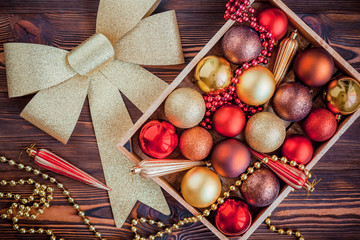 Wooden box filled with Christmas decorations on wooden background. Christmas or new year preparations. . Flat lay various Christmas toys in a box, top view.