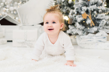 Baby girl on a background of Christmas trees, lights and gift boxes