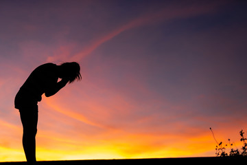 Silhouette woman standing sad in the sunset.