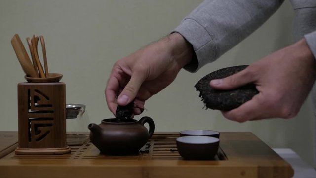 man break puer tea and put it in a clay teapot. Chinese tea ceremony