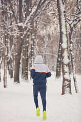 Man jogging in snowy park and cold weather.