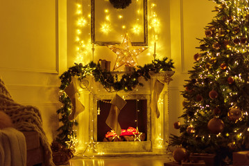 Christmas interior in the living room at evening in lights - fireplace, Christmas tree and chair