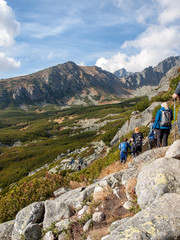 Fototapeta premium Hikers on trail at Great Cold Valley, Vysoke Tatry (High Tatras), Slovakia. The Great Cold Valley is 7 km long valley, very attractive for tourists