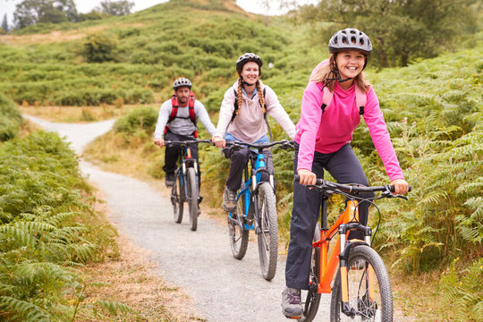 Pre-teen Girl Riding Mountain Bike With Her Parents During A Family Camping Trip, Close Up