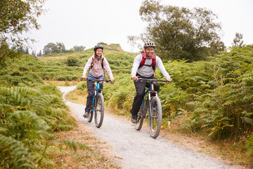 Young adult couple riding mountain bikes in the countryside, full length