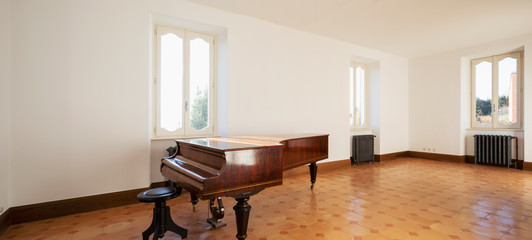 Empty room with antique piano and vintage heaters