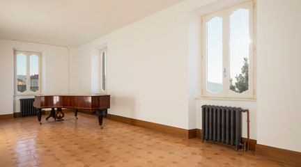 Empty room with antique piano and vintage heaters