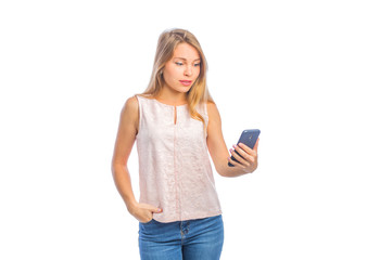 A young woman with a make-up with one hand holds the phone and looks into it, and the other hand in the pocket of jeans