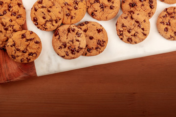 An overhead photo of chocolate chip cookies on a dark rustic wooden table with copyspace