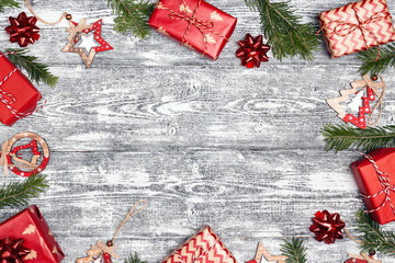 Frame of Christmas gifts with decorations and copy space on grey wooden background.