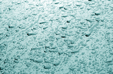 Water drops on car surface in cyan tone.