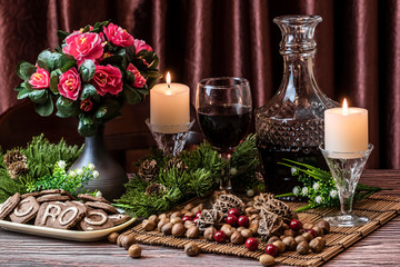 Christmas still life - flowers, candles, walnuts, hazelnuts, red currants, sweet biscuits and red wine