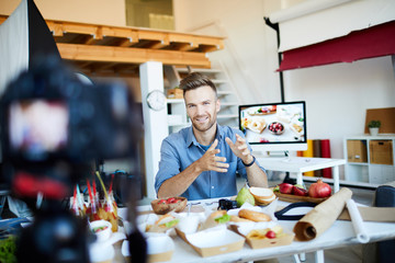 Portrait of handsome man filming cooking show or blog and speaking to camera, copy space