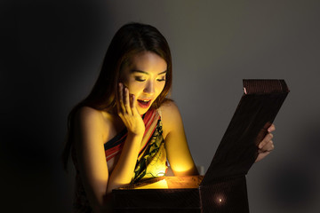 Asian woman opening mystic book box magical light dark background