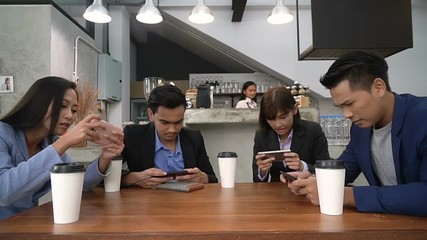 Businessman and women spend their free time at coffee shop by playing game on phone together. They have a good teamwork as when they work at office too.