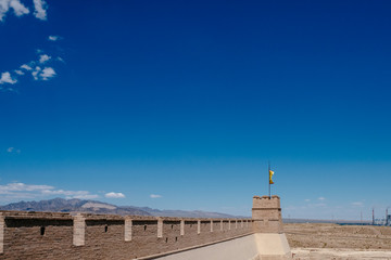Corner tower and wall with yellow flag under blue sky, at Jiayu Pass, in Jiayuguan, China