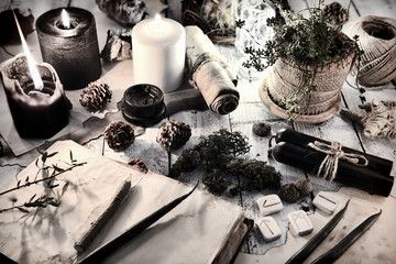 Still life with black and white candles, runes, cones and open diary book on table. Magic gothic...