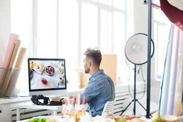 Back view portrait of modern photographer using computer while editing pictures of food in studio, copy space