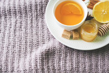 Cup of tea with lemon and cookies, honey and cinnamon sticks, star anise on the blanket.. Christmas, winter concept.