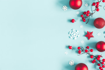 Christmas or winter composition. Frame made of snowflakes, balls and red berries on pastel blue background. Christmas, winter, new year concept. Flat lay, top view, copy space