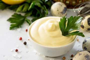 Mayonnaise Sauce close-up. Homemade mayonnaise sauce in a white bowl on a light stone table.