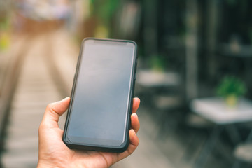 Woman hand using smartphone and laptop with cafe shop sunlight  shade to object beautiful background.