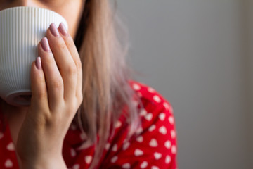 girl in pajamas drinking a drink in a mug.