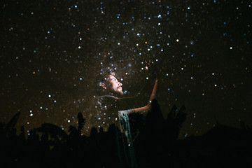 A man looks away at the background of the stars, in the dark glow face from the phone
