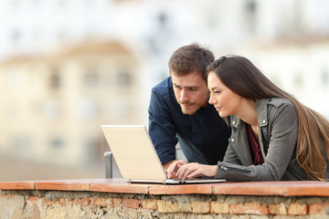 Couple using a laptop in a terrace on holiday