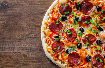 Pizza with Mozzarella cheese, pepperoni, tomato, pepper, olive, salami. Italian pizza on wooden table background