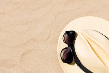 Fototapeta na wymiar summer holidays and vacation concept - straw hat and sunglasses on beach sand