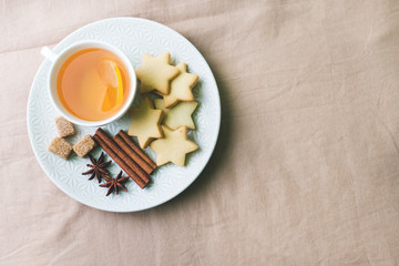 Cup of tea with lemon and cookies, honey and cinnamon sticks, star anise on the blanket.. Christmas, winter concept.