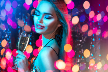 Sexy model girl with glass of champagne at disco party, drinking champagne over holiday glowing...
