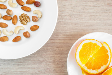 Assorted Nuts, Orange Slices On White Plates On Wooden Table. Healthy Organic Snack, Breakfast, Food Ingredients. Flat Lay Top-Down Composition.