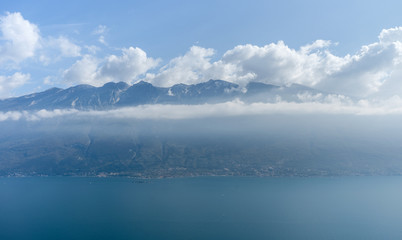 Breathtaking view of the lake garda and the mountain range with clouds  in the background
