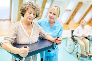 Therapeutin hilft Seniorin mit dem Rollator