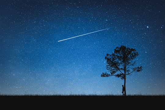 Silhouette Of Man Standing On Mountain And Night Sky With Shooting Star. Alone Concept.