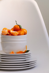 tangerines on a white bowl on a white chair.