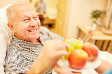 Pflegehilfe serviert altem Mann Obst