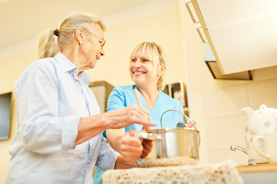 Senior Frau und Pflegehilfe kochen zusammen