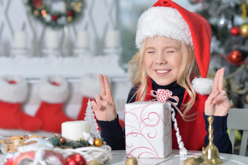 Portrait of happy girl in Santa hat sitting  with Christmas pres