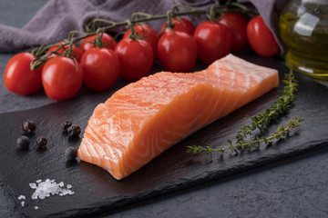 Salmon steak with spices on black stone background