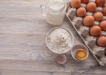 Fototapeta na wymiar Bakery ingredients - flour, eggs, milk, yolk on a table. Top view. Space for text